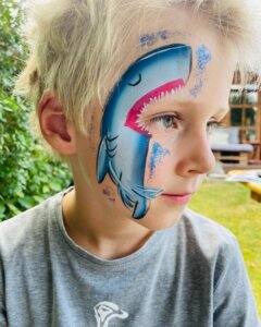 junge_lächelnd_geschminkt_03_haifisch_blau_hellblau_pink_zähne_glitzer