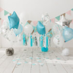 Festive background decoration for birthday celebration with gourmet cake and blue balloons in studio, cake smash first year concept